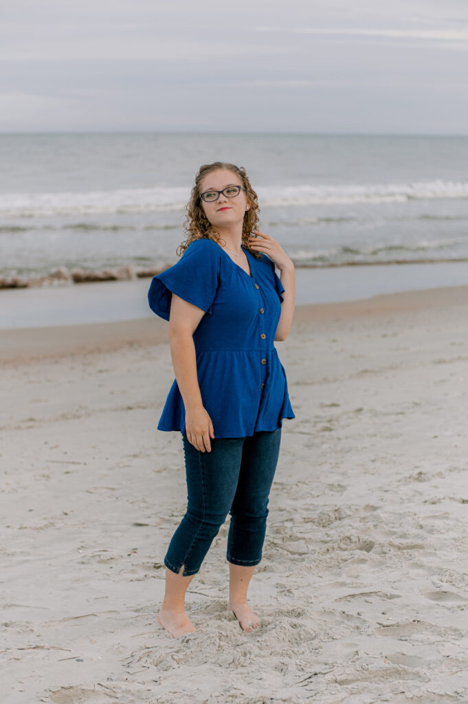 Girl in navy blue shirt, wind flared sleeve, and capris at the beach.