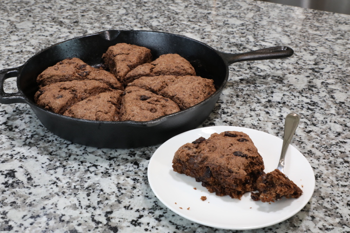 Chocolate cherry scones in cast iron skillet with scone on a white plate