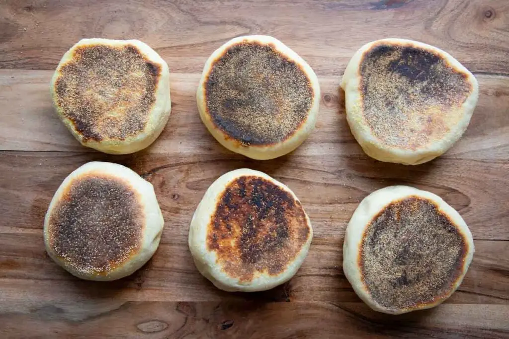 English muffins stacked on each other. Sitting on wooden cutting board,