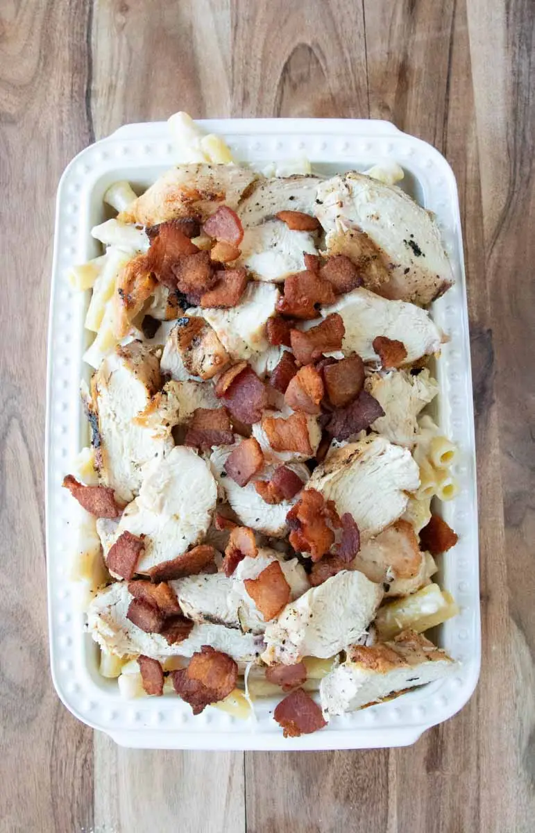 Chicken alfredo baked ziti in white dish on wooden board