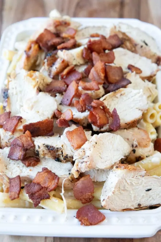 Chicken alfredo baked ziti in white dish on wooden board