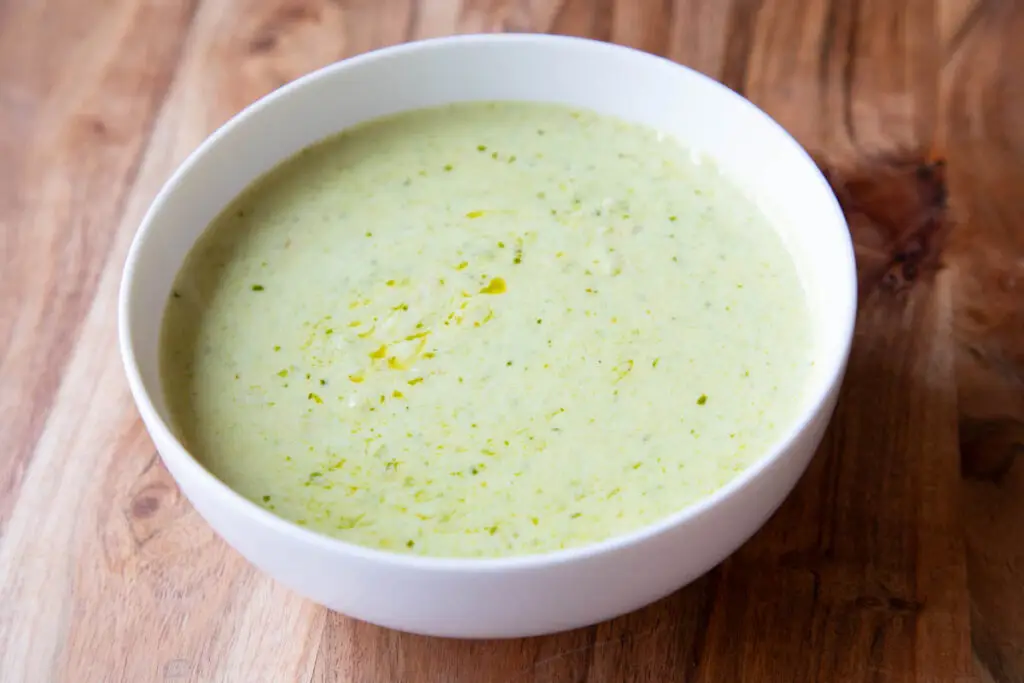 Creamy pesto pasta sauce in white bowl on wooden surface